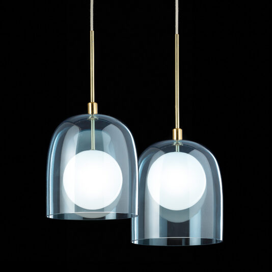 Contemporary Long Glass Dome Pendant Light Two Contemporary Long Glass Dome Pendant Lights with brass fixtures hang against a black background. The lights feature clear, dome-shaped glass shades that reveal spherical frosted bulbs inside, emitting a soft glow. The design is elegant and minimalist.