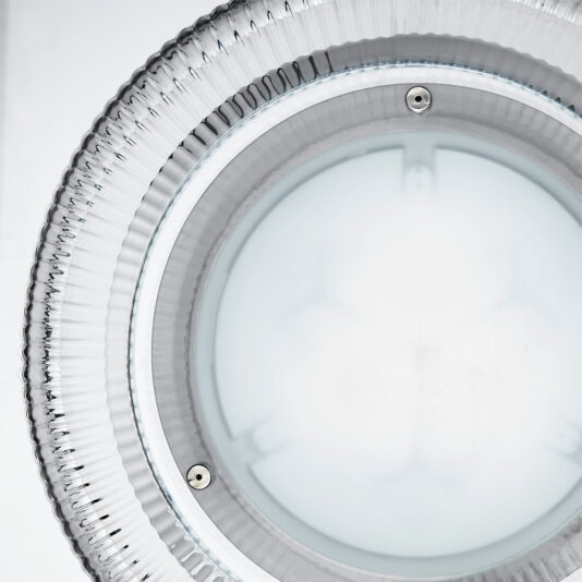 Contemporary Ribbed Glass Ceiling Light Close-up shot of the Contemporary Ribbed Glass Ceiling Light, featuring a transparent, ribbed outer rim and a frosted inner surface. The light is turned on, emitting a bright white glow, with two small screws visible on the rim.