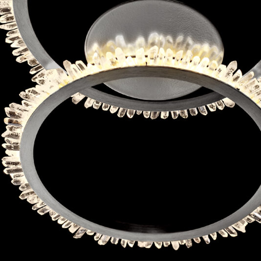 A close-up image of the Double Ring Quartz Crystal Nickel Ceiling Light, showcasing its elegant design with overlapping rings adorned in quartz crystal-like elements that emit a soft, glowing light. The sparkling beauty of the chandelier is accentuated against a black background.