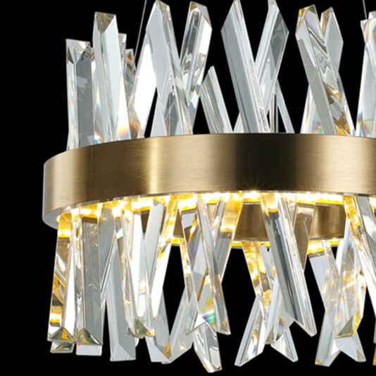 Exclusive Small Brass Pendant Light A close-up of the Exclusive Small Brass Pendant Light, featuring vertical crystal prisms arranged in an overlapping pattern and encircled by a polished gold band. The crystals reflect light beautifully, creating a luxurious and modern aesthetic. The background is pitch black.