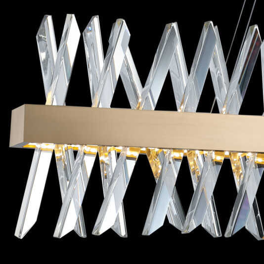 Narrow Brass Crystal Chandelier The Narrow Brass Crystal Chandelier features a sleek, modern design with a narrow rectangular metallic bar suspended horizontally. Crystal shards arranged in an X-pattern hang from the bar, reflecting light to create a prismatic effect against a black background.