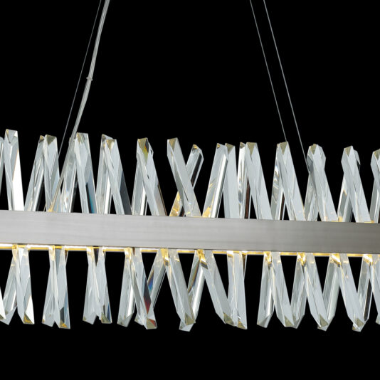Narrow Nickel Crystal Chandelier The Narrow Nickel Crystal Chandelier boasts a sleek, modern design with a row of elongated, twisted crystal-like elements arranged in an eye-catching zigzag pattern. Suspended by thin wires against a black background, this fixture highlights its contemporary and elegant aesthetic.