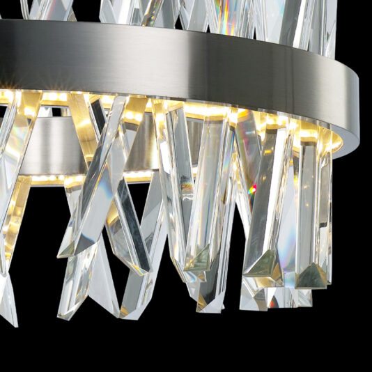 Exclusive Round Nickel Chandelier A close-up image of the Exclusive Round Nickel Chandelier showcases its modern design, featuring a brushed metal ring adorned with LED lights and numerous clear, elongated crystals that hang elegantly from it. The crystals brilliantly reflect light, creating a mesmerizing sparkling effect against the black background.