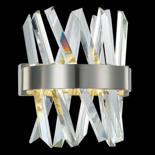 The Exclusive Crystal Nickel Wall Light boasts a modern wall sconce design with a brushed metal base and intersecting, angled glass or crystal pieces that emit light to create a reflective and refractive pattern reminiscent of a geometric, crisscross design.