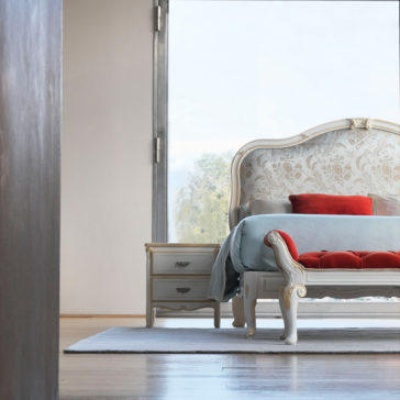 Elegant Classic Style Bed A bedroom features the Elegant Classic Style Bed, which has a light blue tufted headboard and red cushions, adding a touch of sophistication. The ornate bed boasts a wooden frame with intricate detailing. Beside it stands a two-drawer nightstand. A large window floods the room with natural light, accentuating its minimalist decor.