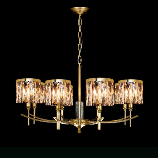 The High End 8 Arm Gold Chandelier, featuring eight arms each holding a cylindrical, faceted crystal shade, is suspended from the ceiling by a matching gold chain. Set against a black background, its lights are on and cast a warm glow through the crystal shades.