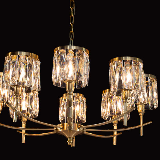 The High End 8 Arm Nickel Chandelier, featuring a luxurious gold finish and multiple crystal lampshades each enclosing a light bulb, hangs gracefully from a chain against a black backdrop. The crystals capture and scatter the light, resulting in a mesmerizing sparkling effect.
