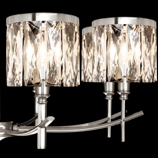 A close-up of a two-light wall sconce featuring sleek, metallic arms and cylindrical lampshades adorned with vertically aligned, faceted crystal strips. The sconce is lit, creating a shimmering effect against a black background, complementing the elegance of any high-end space like the High End 8 Arm Nickel Chandelier would.