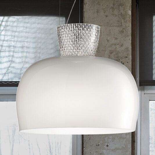 The Modern Glass Dome Pendant Light, featuring a smooth white finish and textured clear glass top detail, hangs elegantly from the ceiling by wires. The background showcases a stylish combination of a concrete wall and window, providing a partial view of the outdoors.