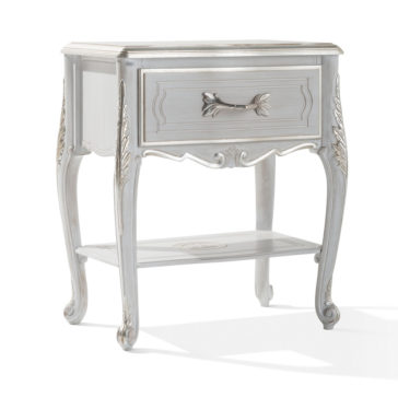The Ornate Bedside Cabinet With Drawer is a vintage-style nightstand that showcases a distressed white finish. It features an elegant drawer with an ornate handle and decorative floral carvings. The table boasts curved legs with detailed carvings and an open lower shelf for added charm.