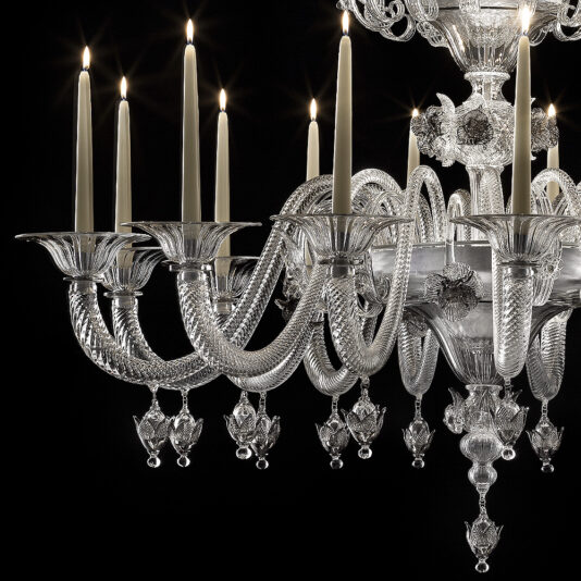Ornate Floral Glass Chandelier With Candle Details A close-up view of the Ornate Floral Glass Chandelier With Candle Details, showcasing its elegant design adorned with intricate floral patterns and multiple candle-like lights. The chandelier features detailed crystal arms and hanging ornaments, adding a luxurious and ornate touch to its overall appearance.