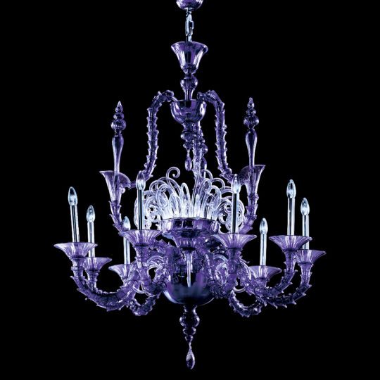 The Classic Ornate Purple Glass Chandelier, featuring intricate detailing, is suspended against a black background. It boasts multiple arms adorned with candle-like lights, showcasing its elegant and ornate design.