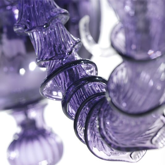 Classic Ornate Purple Glass Chandelier Close-up of an intricate, purple glass sculpture with swirling and ribbed details. The translucent material reflects light, showcasing the delicate craftsmanship and smooth curves reminiscent of a Classic Ornate Purple Glass Chandelier against a blurred background.