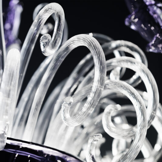 Classic Ornate Purple Glass Chandelier Close-up image of intricate spirals from the Classic Ornate Purple Glass Chandelier against a dark background. The smooth, glossy texture and delicate curves of the transparent glass evoke timeless elegance. Hints of purple accents in some sections enhance its sophisticated and artistic appearance.