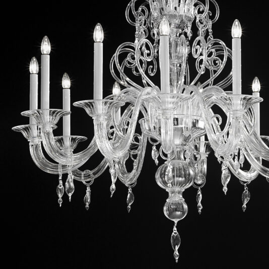 Ornate Traditional Clear Glass Chandelier A close-up of the Ornate Traditional Clear Glass Chandelier reveals several candle-like light bulbs. The clear, intricate glass arms and delicate hanging crystal pendants gleam against a dark, black background.