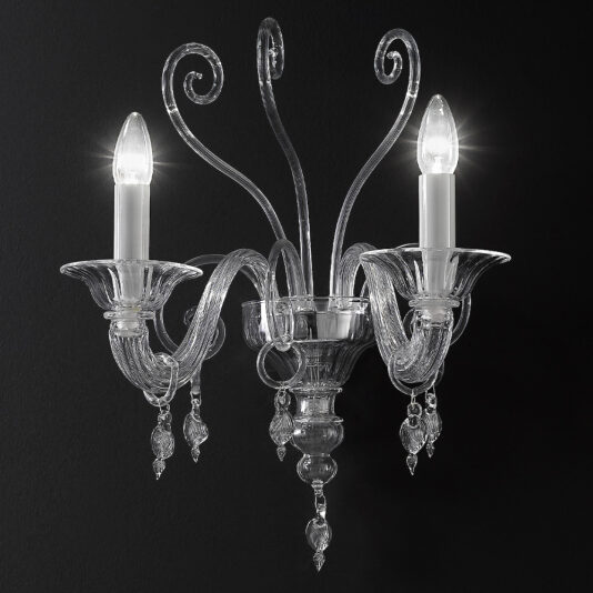 The Traditional Clear Glass Wall Light is a decorative, two-light wall sconce featuring a black background. It includes elegant arms and ornate detailing with small hanging glass ornaments. Each light is topped with a flame-shaped bulb that emits bright light.