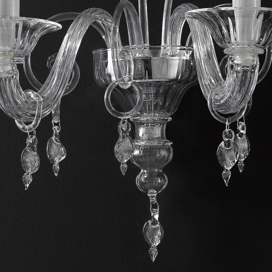 A close-up view of the Traditional Clear Glass Wall Light reveals its luxurious, transparent glass design with intricate, curving arms and teardrop-shaped hanging ornaments. Set against a black background, this wall light exemplifies detailed craftsmanship and elegance.