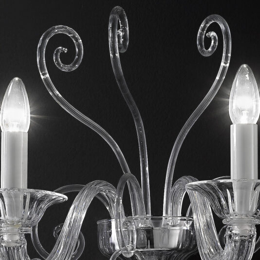 Close-up of the Traditional Clear Glass Wall Light against a dark background. The elegant chandelier showcases intricate glass arms with curved designs, adorned with faux candle-shaped light bulbs, each enclosed in a clear glass sleeve. Soft reflections dance off the exquisite glass surfaces.