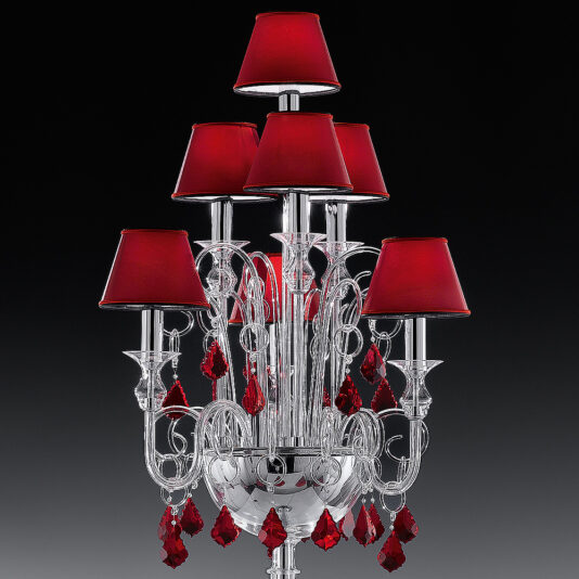 Traditional Floor Lamp With Red Crystal Drops A luxurious, multi-tiered chandelier with an intricate silver frame adorned with red crystals and reminiscent of the Traditional Floor Lamp With Red Crystal Drops. The chandelier features several red lampshades, adding a touch of elegance and sophistication. Set against a dark background, the colors and details truly stand out.