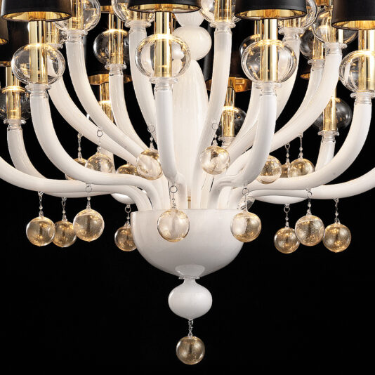 Traditional Glass Orb Detail Chandelier Here's a close-up of the Traditional Glass Orb Detail Chandelier, featuring an elegant white base with multiple curved arms. Each arm culminates in a detailed glass orb, accompanied by additional glass spheres dangling from small chains. Emitting a golden light, the chandelier creates a luxurious ambiance against the dark background.