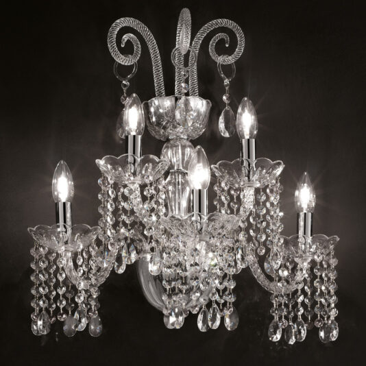 Introducing the Classic Glass Wall Light With Crystal Drops: a luxurious classic crystal chandelier with five light bulbs arranged in a circular pattern. This exquisite fixture boasts ornate designs and hanging crystal prisms, reminiscent of an elegant glass wall light with crystal drops, beautifully set against a dark background to highlight its sparkling details.