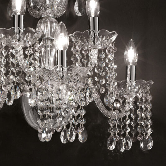 Classic Glass Wall Light With Crystal Drops A close-up of the Classic Glass Wall Light With Crystal Drops, featuring multiple candle-shaped light bulbs, intricate glass details, and dangling crystal drops against a dark background. The elegant and ornate wall light emits a bright, sparkling glow that is beautifully reflected by the crystals.
