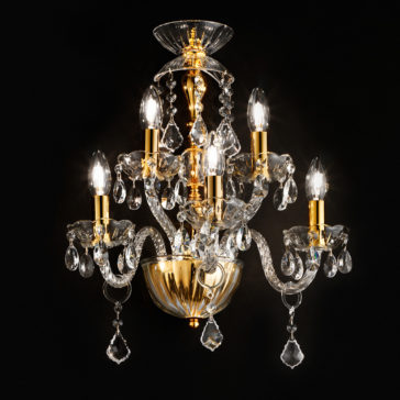 A luxurious, classic gold and crystal chandelier with intricate designs and multiple arms, each holding a lit candle-like light bulb. The chandelier features hanging crystal ornaments, adding an elegant and opulent touch against a dark background, reminiscent of the Classic Gold 5 Arm Wall Light With Crystal Drops.