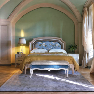 Classic Louis Style Upholstered Bench A bedroom with green arched walls and ceiling, featuring a bed with a tufted blue headboard adorned with floral designs, draped in yellow and white bedding. The room includes matching white nightstands, one of which holds a lamp. At the foot of the bed is a Classic Louis Style Upholstered Bench, while light curtains complete the serene look.