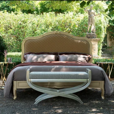 Elegant Ornate Classic Style Bed In a serene garden, the Elegant Ornate Classic Style Bed with an intricate tufted headboard and dark bedding takes center stage. At its foot, a stylish bench enhances the scene, surrounded by lush greenery and a classical statue for a picturesque setting.