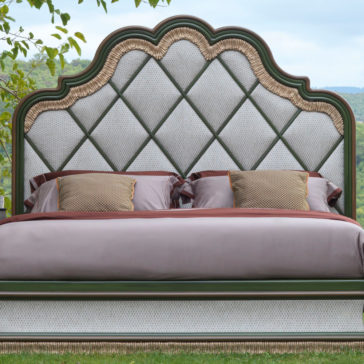 The Exclusive Bed With Tassel Design Detail is elegantly placed outdoors, showcasing a stylish upholstered headboard adorned with a diamond pattern and intricate green and gold tassels. Draped in light gray bedding and accented with multiple pillows, this luxurious bed is set against a picturesque, green landscape.