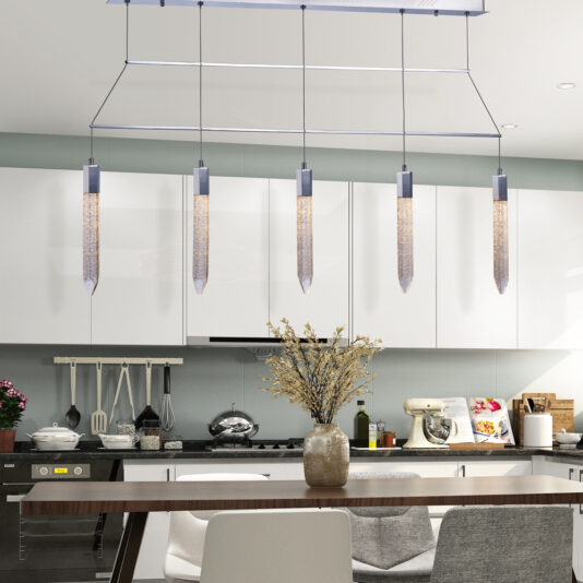 The modern kitchen features white cabinets and a clean, minimalist design. An **Exclusive Chrome Pendant Light Bar** elegantly illuminates a wooden dining table paired with white and gray chairs. A vase with dried flowers serves as the centerpiece on the table, while appliances and kitchenware can be seen in the background.
