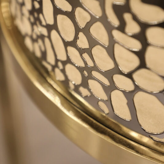 Exclusive Curved Bar Stool Close-up photo of an intricate, abstract metal mesh design with gold and bronze tones on the Exclusive Curved Bar Stool. The mesh features irregular, organic-shaped cutouts, creating a pattern that appears both delicate and decorative. The image focuses on a section of the object.