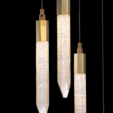 Exclusive Gold Pendant Light Cluster The Exclusive Gold Pendant Light Cluster features three pendant lights with textured, elongated glass shades and sleek metal accents, hanging elegantly from the ceiling against a black background. This cluster of lights emits a warm, inviting glow.