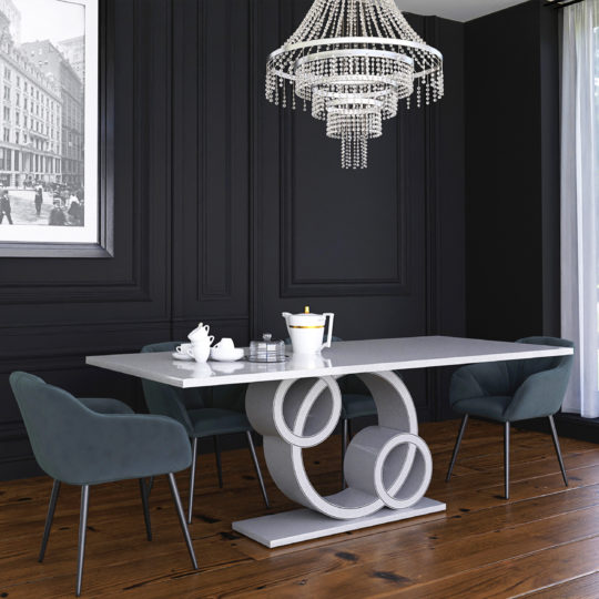 A sleek dining area showcases the Exclusive Marble Dining Table, distinguished by its unique circular base. Surrounding it are four dark upholstered chairs, while a chic crystal chandelier hangs above. The dark paneled wall is adorned with black and white cityscape artwork, and a large window allows natural light to flood in.