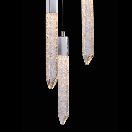A close-up image of the Exclusive Triple Chrome Pendant Light showcasing its crystal-like elongated, cylindrical shapes. Each pendant features a textured surface that emits a soft, warm glow as they hang at varying lengths against a black background.