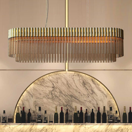 An elegant, high-end oval chandelier with a tiered, metallic and glass-rod design hangs from the ceiling above a marble-topped bar. Below, various bottles of wine and liquor are arranged in front of a marble background with a semi-circular decorative arch.