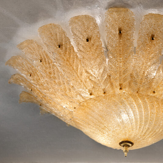 Large Amber Glass Leaf Ceiling Light The Large Amber Glass Leaf Ceiling Light, grand and splendid, adorns the ceiling with its intricate golden leaf-like crystal elements that radiate outward in a fan-like pattern. This luxurious chandelier emits a warm, golden glow, enhancing its opulent appearance.