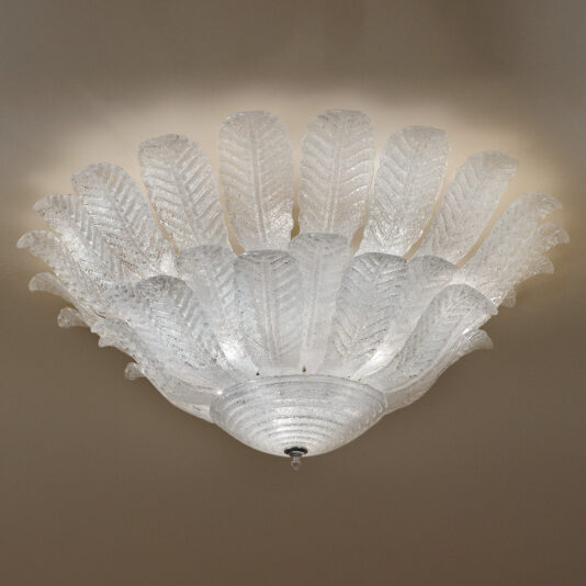 The Large Double Tier Glass Leaf Ceiling Light is a chandelier featuring elaborate glass leaves arranged in a circular pattern, emitting a soft, diffused light. The design includes textured, translucent leaves that fan outwards, reminiscent of an elegant floral or feather motif.