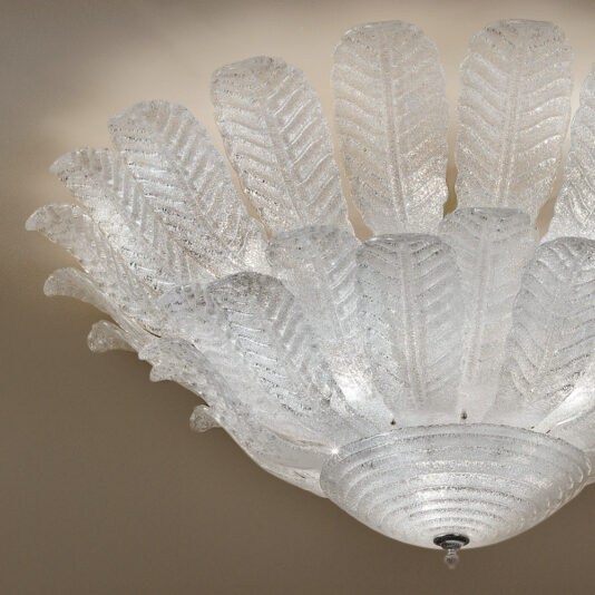 The Large Double Tier Glass Leaf Ceiling Light features a symmetrical arrangement of translucent, leaf-shaped glass pieces radiating outward in a circular pattern, creating an elegant and intricate design. The light emits a warm, soft glow.