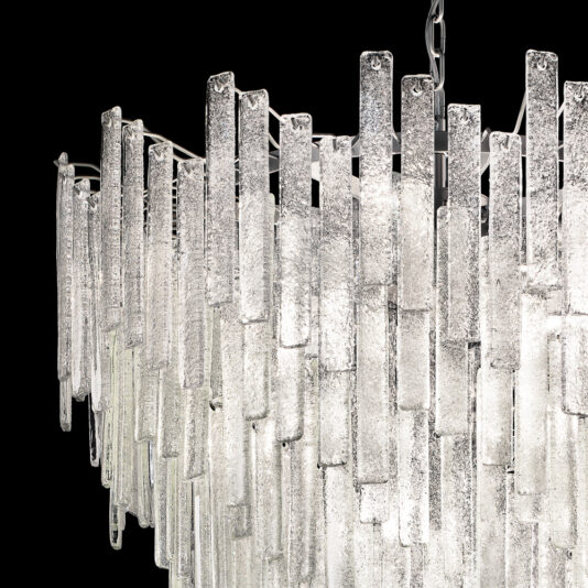 Large Modern Glass Chandelier A close-up image of the Large Modern Glass Chandelier features multiple vertical glass rods arranged in descending order, creating a cascading effect. The textured surface of the rods adds depth, and the chandelier is set against a black background.