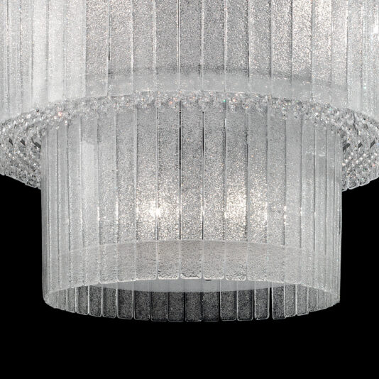 Large Modern Tiered Glass Chandelier A close-up view of the Large Modern Tiered Glass Chandelier, showcasing multiple tiers of vertically aligned, clear glass panels with a textured, frosted appearance. The illuminated panels create a sparkling effect against the dark background.