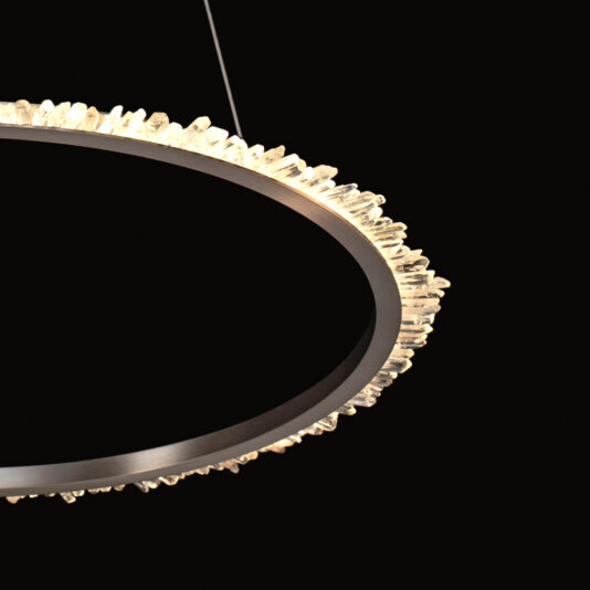A close-up shot of the Large Quartz Crystal Nickel Round Chandelier in a dark setting. The chandelier, adorned with numerous small quartz crystal elements around its circular rim, emits a warm glow that contrasts beautifully with the dark background. Its modern and elegant design, accentuated by a nickel finish, highlights its unique craftsmanship.