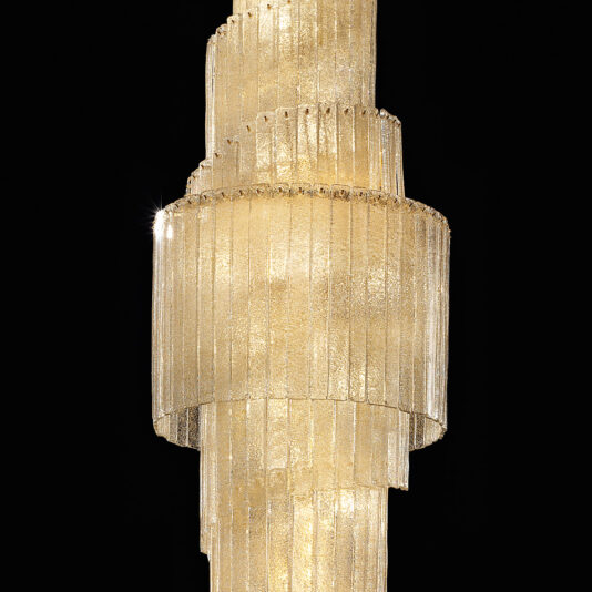 Large Tiered Amber Glass Chandelier The Large Tiered Amber Glass Chandelier boasts a luxurious design with vertically tiered, textured amber glass panels, each arranged in a cylindrical pattern to radiate warm golden light against a pitch-black background.