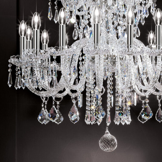 Large Two Tier Blown Glass Chandelier With Crystals A close-up image of the Large Two Tier Blown Glass Chandelier With Crystals, showcasing its intricate dangling crystal ornaments. The chandelier boasts numerous candle-shaped light bulbs, reflecting light and creating a shimmering effect against a dark background.
