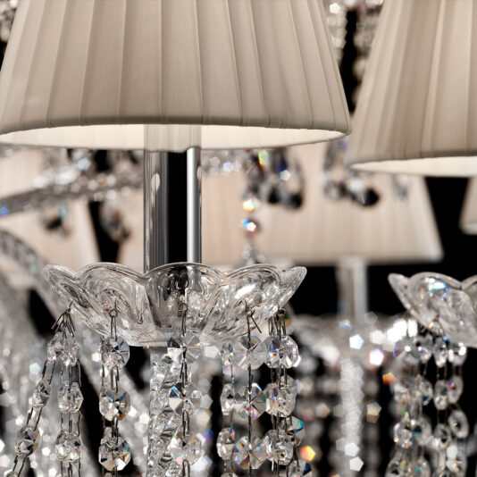 A close-up of the Large Two Tier Crystal Chandelier With Shades reveals its intricate details. The crystal ornaments suspended from the central support gleam brilliantly, while the soft white lampshades provide an elegant accent to the decor.