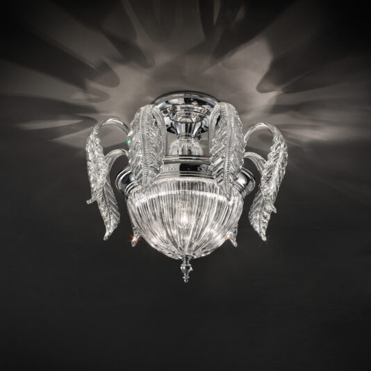A close-up of the Luxury Acanthus Empire Glass Ceiling Light reveals its ornate design, featuring a polished metal base. The light fixture resembles a blooming flower, with petal-like crystal glass elements encircling a central ribbed glass dome. It is set against a dark background that emits a subtle glow.