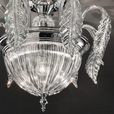 Luxury Acanthus Empire Glass Ceiling Light A close-up shot of the Luxury Acanthus Empire Glass Ceiling Light showcases its elegant Italian design with intricate details. The crystal ceiling light features a central glass orb with vertical ribbing, surrounded by several clear, curved glass leaves extending outward, each adorned with delicate patterns. Light reflects off the glass, creating a sparkling effect.