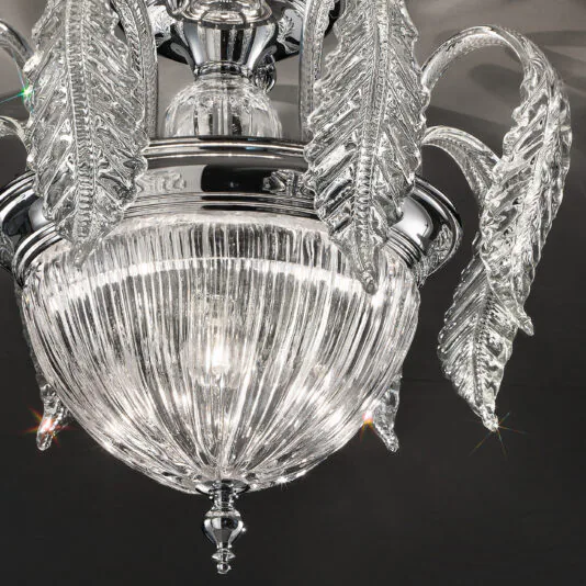 A close-up shot of the Luxury Acanthus Empire Glass Ceiling Light showcases its elegant Italian design with intricate details. The crystal ceiling light features a central glass orb with vertical ribbing, surrounded by several clear, curved glass leaves extending outward, each adorned with delicate patterns. Light reflects off the glass, creating a sparkling effect.