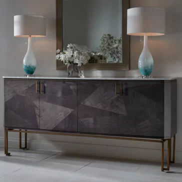 This sophisticated Luxury Marble Top Veneer Sideboard features a geometric patterned dark wood veneer and is adorned with two stylish blue and white gradient table lamps alongside a floral arrangement. A large mirror above it reflects the elegance, while the sideboard, with its sleek metal legs, rests on a polished white marble floor.