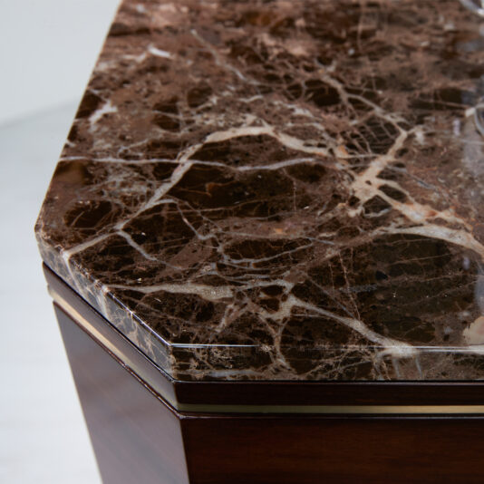 A close-up shot of a polished, brown marble tabletop with light veining. The table has beveled edges and a rosewood veneer base, exuding the same luxury seen in the Luxury Rosewood Veneer Drinks Cabinet while showcasing the intricate natural patterns of the marble surface.